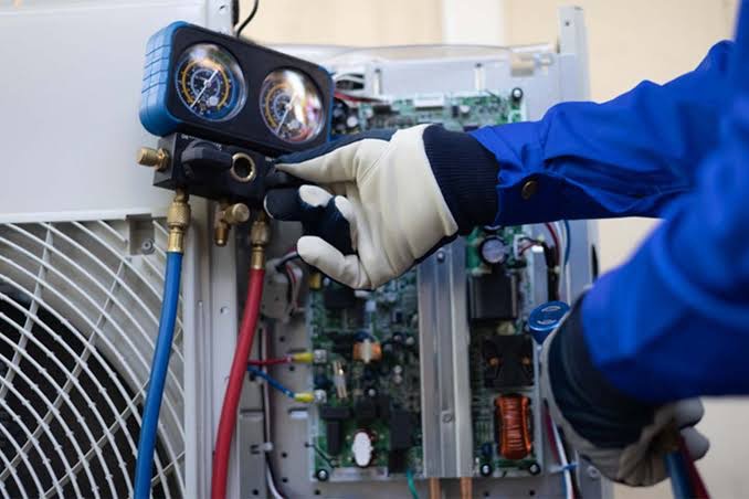 Clean Air Maintenance technician checking HVAC system pressure with professional gauges
